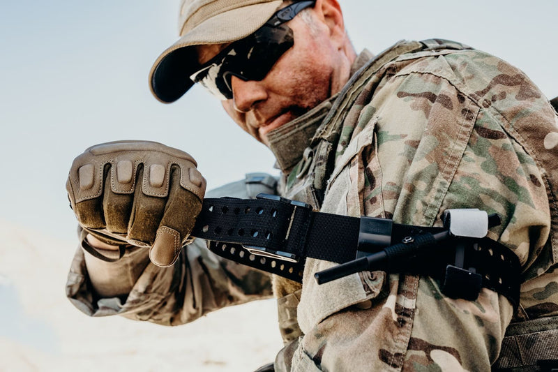 Soldat drar åt en tourniquet på överarmen